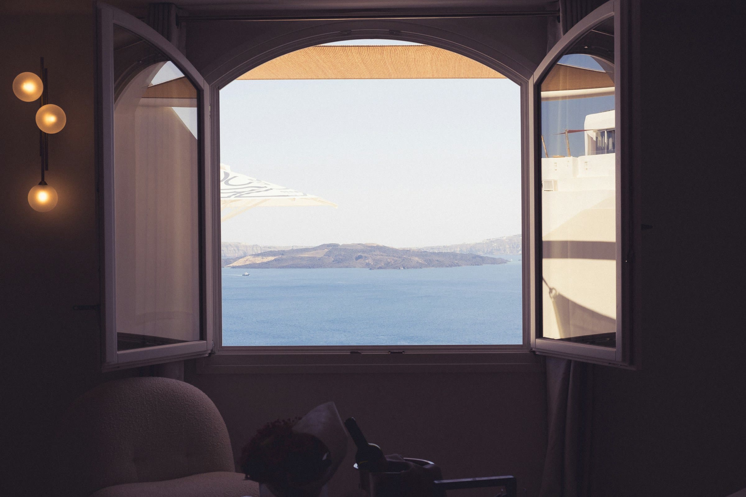 A room with an open window looking out to the ocean, evoking travel discovery
